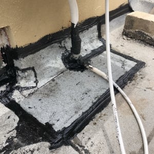 איטום גג עם חומר שחור סביב צינורות