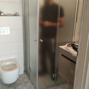 מקלחון זכוכית עם דלתות מטושטשות ומקלחת עליונה