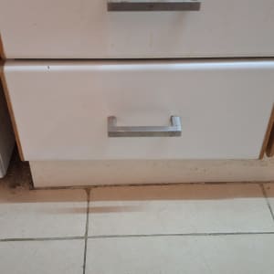 ארון מטבח עם ידיות מתכת על רצפת קרמיקה