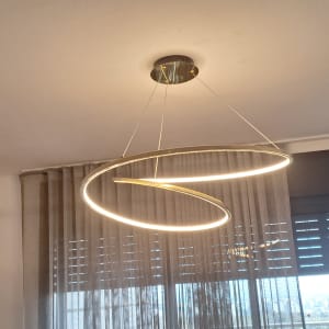 גוף תאורה מעוצב תלוי מהתקרה בחדר עם וילונות