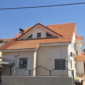 עבודה על גג רעפים אדום של בית פרטי באמצעות התזה בלחץ