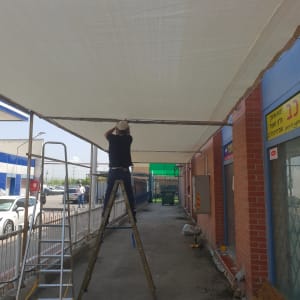 אדם מתקין סוכך בד על מסגרת מתכת