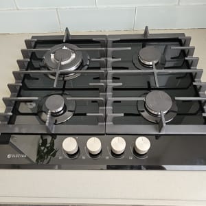 כיריים גז שחורות עם ארבעה מבערים וכפתורים לבנים