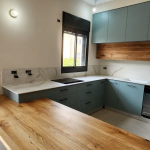 מטבח עם משטח שיש לבן וארונות ירוקים