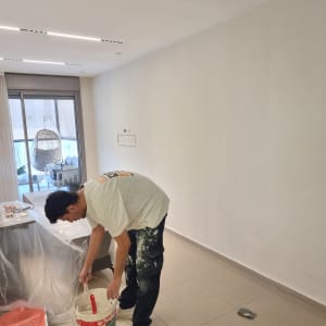 אדם צובע קיר בחדר עם דלי צבע