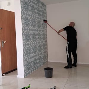 אדם מנקה קיר עם מטאטא, דלי ומים על הרצפה