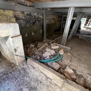שטח מתחת למבנה עם קורות מתכת ואבנים
