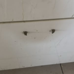 ארון מטבח עם ידיות שבורות על רצפה מרוצפת