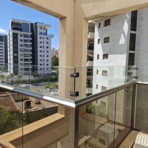 מעקה זכוכית במרפסת עם נוף לבניינים גבוהים