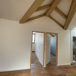 קירות גבס לבנים עם דלתות עץ ותקרה משופעת