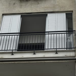 מרפסת עם מעקה מתכת ותריסים לבנים