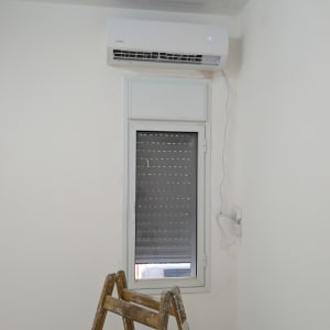מזגן מותקן על קיר מעל חלון וסולם