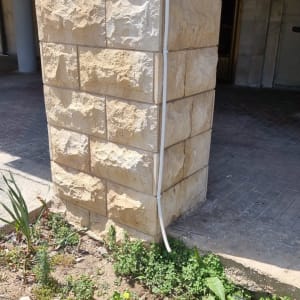 צינור מיזוג אוויר מחובר לקיר אבן חיצוני