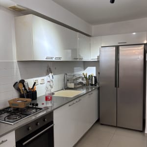 מטבח מודרני עם ארונות לבנים ומקרר נירוסטה
