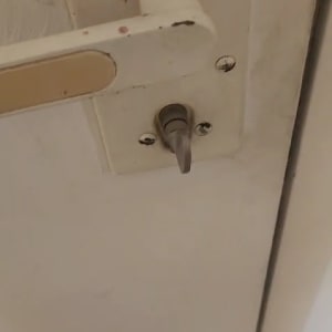 ידית דלת ובריח מתכת על דלת לבנה