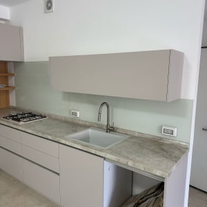 מטבח עם משטח זכוכית מאחורי הכיור והכיריים