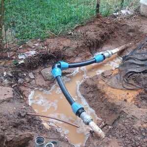 צינור מים עם מחברים כחולים באדמה רטובה