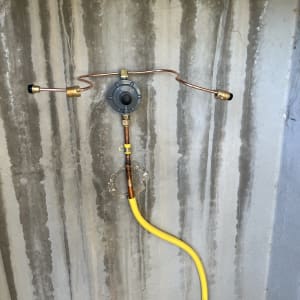 צינור גז צהוב מחובר לקיר בטון עם מחבר מתכת