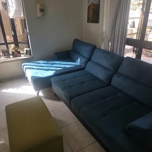 ספת בד כחולה מרופדת והדום תואם בסלון הבית