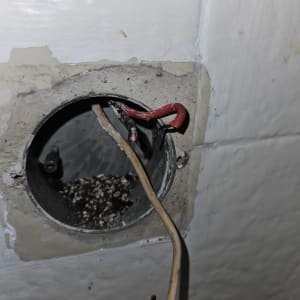 חוטי חשמל חשופים בקופסת חיבורים בקיר