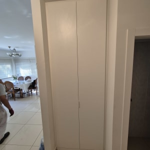 ארון עץ לבן עם דלתות סגורות במסדרון