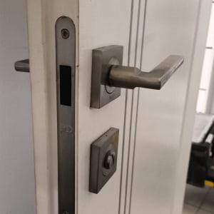 ידית דלת מתכתית עם מנעול על דלת לבנה