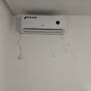 מזגן מותקן על קיר לבן עם כבל חשמל