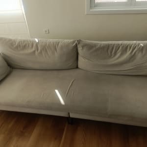 ספה בהירה עם כריות על רצפת עץ