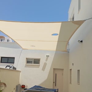 סוכך בד מתוח בין קירות לבנים עם חורים עגולים