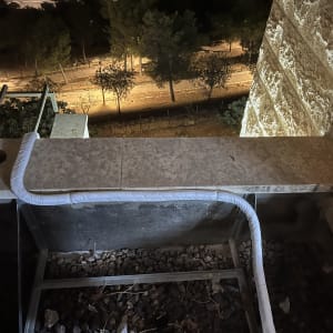 צינור מיזוג אוויר על גג עם אבנים ועצים ברקע