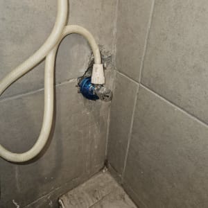 צינור מים מחובר לברז בקיר אריחים אפור