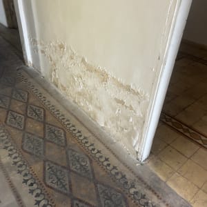 קיר עם סימני רטיבות ונזקי מים בתחתית