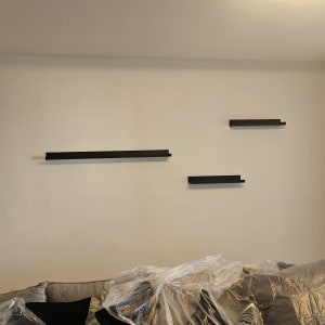 מדפים מותקנים על קיר מעל ספה מכוסה בניילון