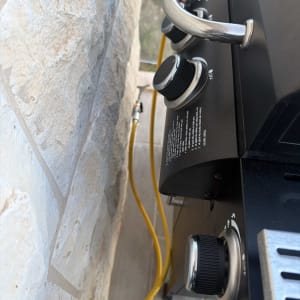 גריל גז עם כפתורי שליטה וצינור גז צהוב
