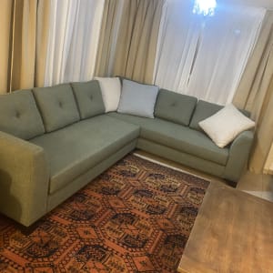 ספה ירוקה עם כריות לבנות על שטיח צבעוני