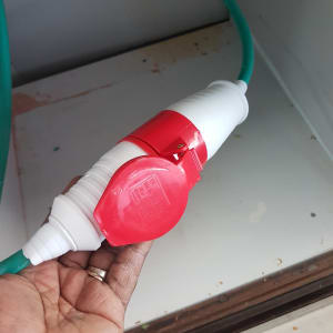 חיבור כבל חשמל עם סרט אדום ביד חשמלאי