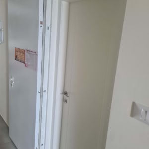 דלת לבנה עם ידית כסופה ומסילה עליונה