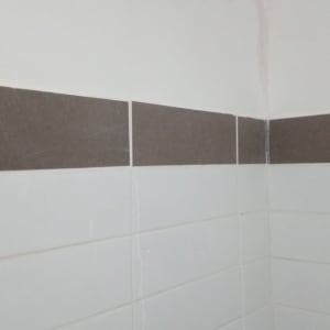 קיר עם אריחים לבנים ותיקון טיח בפינה