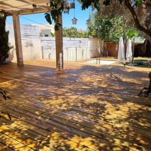 wooden deck with shadows from trees and pergola