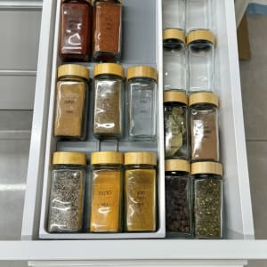 צנצנות תבלינים מסודרות במגירה עם מכסים מעץ