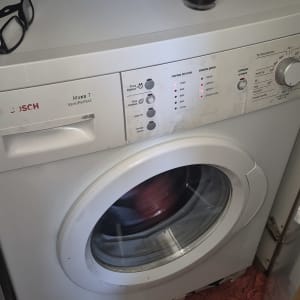 מכונת כביסה עם כוס קפה ומשקפיים על המכסה