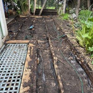 הכנה לגינה עם קרשים ואדמה, צמחים מסביב