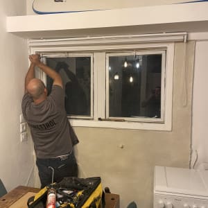 אדם מתקין חלון עם כלים על שולחן