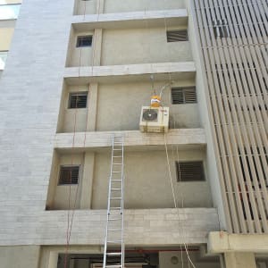 מזגן תלוי על חבלים ליד בניין גבוה