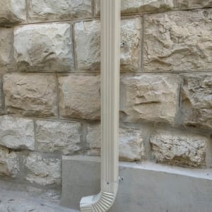 מרזב לבן מחובר לקיר אבן