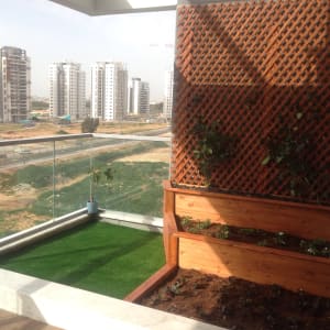 גינה במרפסת עם דשא סינתטי וצמחים במיכלים