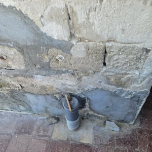 קיר עם צינור ומברשת על רצפה מרוצפת