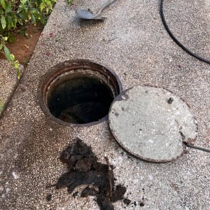 פתח ביוב פתוח עם מכסה בצד, צינור ושאריות לכלוך