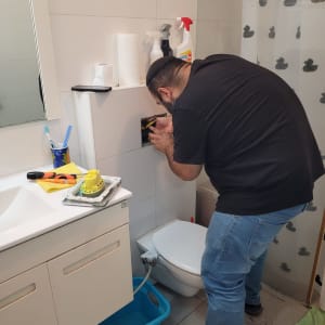 אדם מתקן ניאגרה בחדר אמבטיה עם כלים