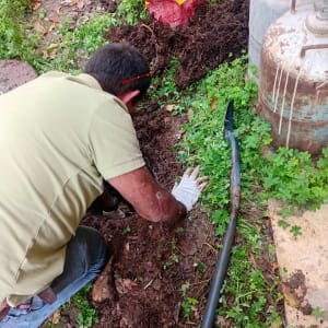 אדם עובד על צינור בגינה עם כלי עבודה